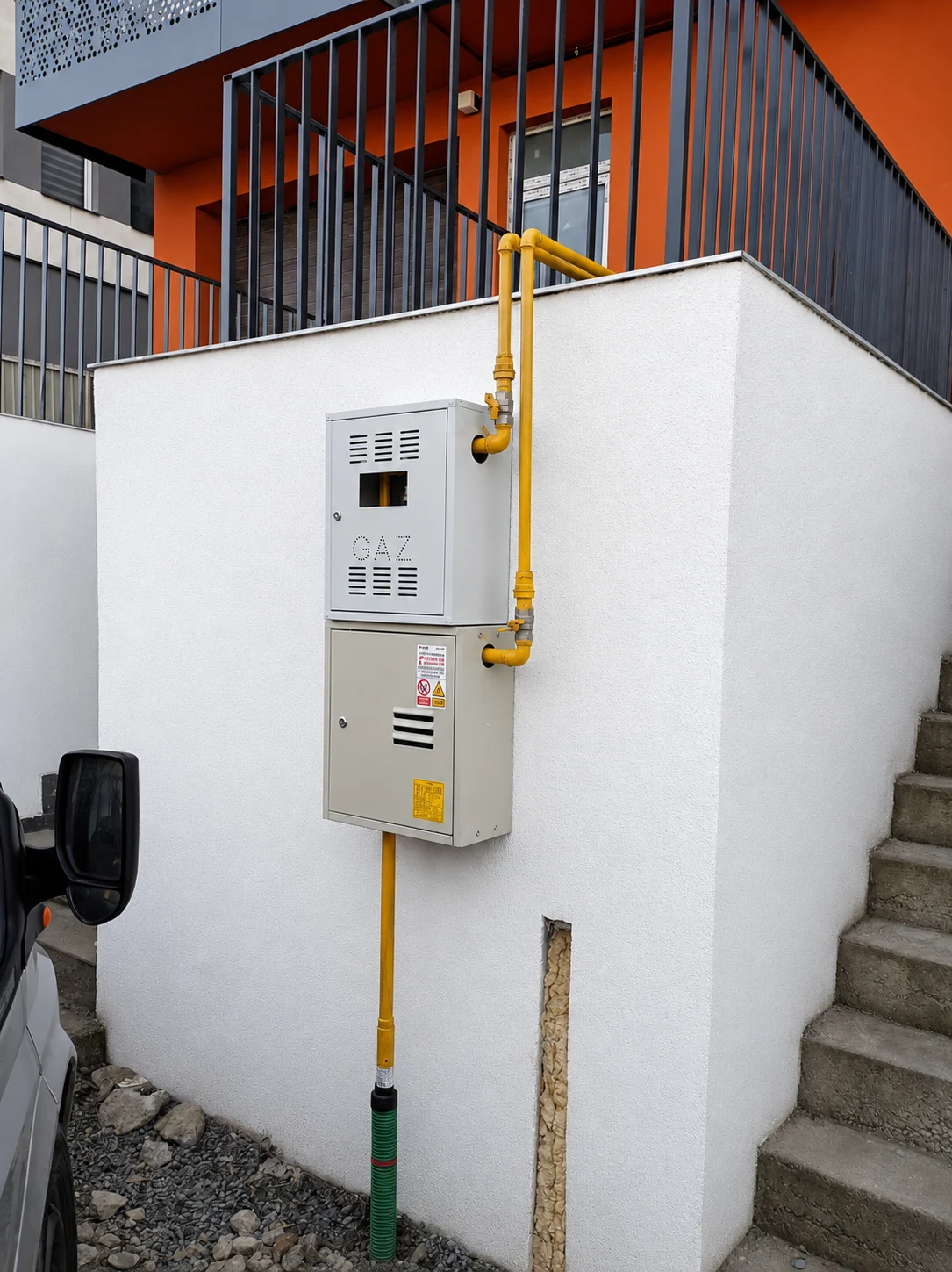Firidă de gaz și țeavă galbenă montate la colțul unei case